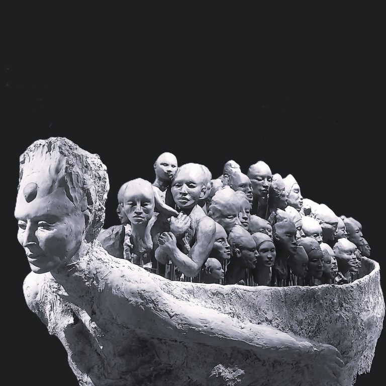 Das Terrakotta-Motiv „El viaje“ von Maria Ballester zeigt eine große Figur, die zahlreiche kleine menschliche Köpfe und Körper wie in einem Boot trägt.