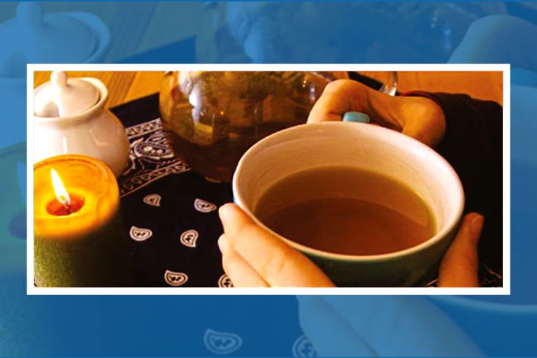 Zwei Hände halten eine Tasse Tee neben einer brennenden Kerze und einer Teekanne auf einem gemusterten Tuch als Symbol für den digitalen Austausch.